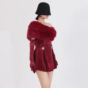 Dettaglio dell'abito natalizio in velluto bordeaux con bordo in pelliccia e strass.