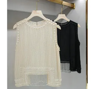 Close-up of elegant cream and black sleeveless vests featuring pearls and fringe detail