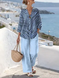Ganzkörperaufnahme von lässiger Streifenbluse und hellblauer Leinenhose für den Urlaub