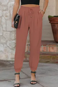 Detailed view of women's high-waisted drawstring cuffed trousers in terracotta red