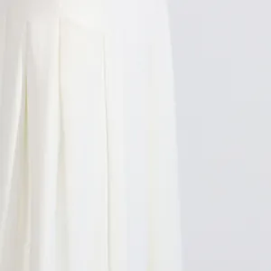 Macro detail shot showing the elegant pleated fabric texture of white wide-leg pants