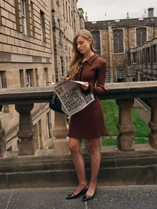 Elegant brown ribbed knit dress with ruffled hem and black polo collar in a classic city scene