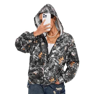 Vrouw in camouflagejack met capuchon en rits die een smartphone vasthoudt voor een selfie