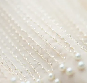 Close-up of elegant beaded fringe and pearl details on a luxury beige vest