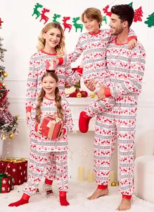 Happy family wearing matching red reindeer print Christmas pajamas in a cozy home setting