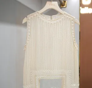 Close-up of elegant cream beaded vest with pearl accents and fringe detail