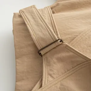 Detail shot of khaki casual apparel strap and metal buckle hardware, fine fabric texture.