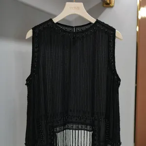 Close-up detail of elegant black mesh vest with intricate beading and fringe