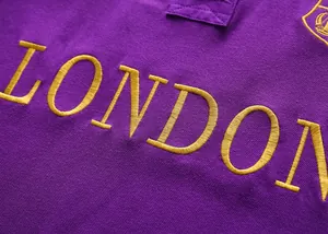 Macro detail of golden London embroidery on purple cotton piqué polo shirt fabric