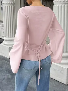 Back view of pink boat neck top featuring flare sleeves and a waist tie-back detail.