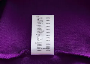 Close-up macro view of 100% cotton material care label on purple polo shirt fabric