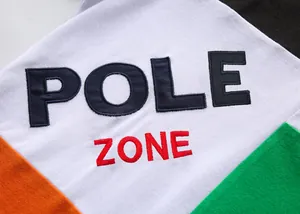Dettaglio del ricamo POLE ZONE di alta qualità su polo in cotone con blocchi di colore