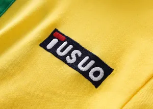 Detalle macro del logotipo bordado en un polo de fútbol brasileño de algodón amarillo
