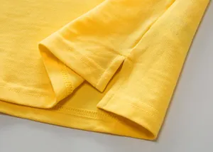 Primer plano de polo de algodón piqué amarillo con detalle de abertura lateral en el bajo