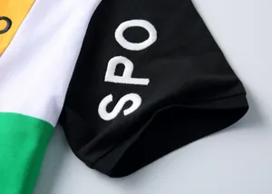 Gros plan d'une manche de polo bicolore avec détails de broderie blanche SPO