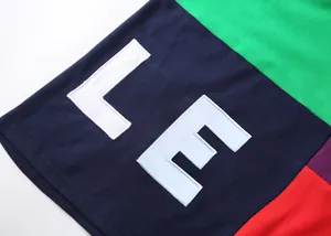 Détail de la broderie des lettres LE sur un polo en coton color-block éclatant