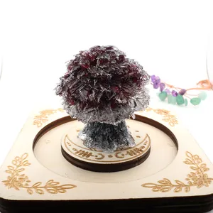 Detailed view of a natural garnet crystal crushed stone tree on a carved wooden base