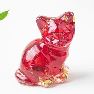 Dettaglio di statuetta di gatto in resina rossa con pietre di cristallo e oro.
