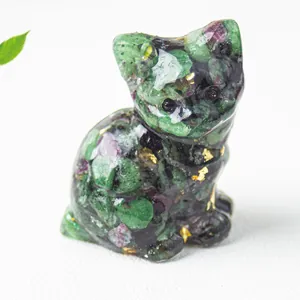 Dettaglio di una statuetta di gatto in resina e cristallo con pietre verdi e oro