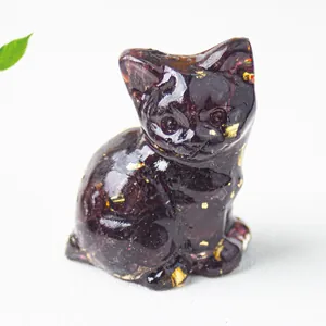 Dettaglio ravvicinato di un gatto in resina con frammenti di cristallo e foglie d'oro.