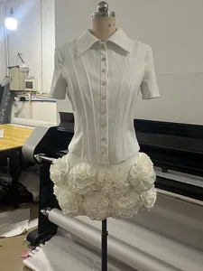 Detailed view of an elegant white slim-fit short-sleeved shirt and 3D floral mini skirt set.