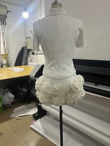Detailed back view of white slim-fit top and 3D floral ruffle skirt on a mannequin