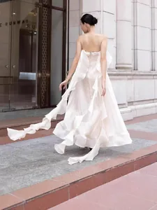 Elegant white strapless evening gown with flowing streamers and ruffle details.
