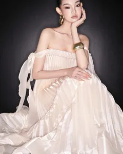 Close-up of elegant off-the-shoulder pleated maxi dress with braided bodice and ribbons