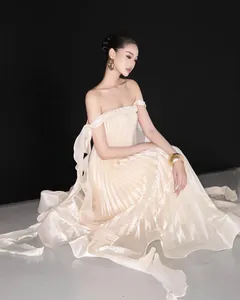 Elegant pleated off-shoulder maxi gown with braided bustier and long flowing streamers.