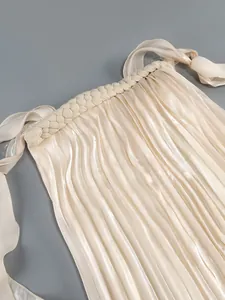 Close-up of elegant pleated dress with braided neckline and ribbon ties