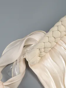 Close-up detail showing the intricate braided shoulder strap and shiny satin fabric of a dress