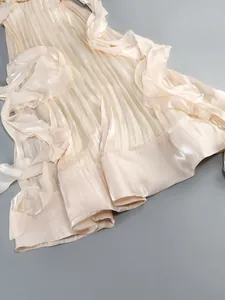 Detail of champagne pleated maxi dress with elegant ruffles and shimmering fabric texture