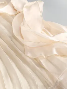 Close-up of elegant cream ruffled and pleated fabric texture on a formal dress