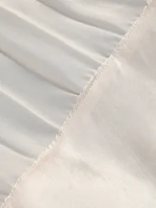 Close-up macro view of champagne pleated satin fabric showing high-quality stitching.