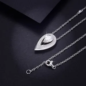 Close-up of pear-shaped moissanite pendant necklace with pavé halo on black background