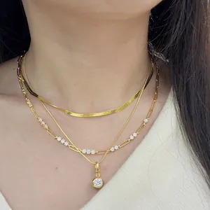 Detailed view of layered gold necklaces with moissanite pendant and paperclip chain style