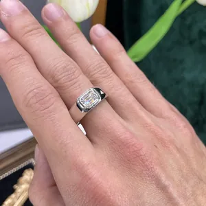 Primo piano di un anello in moissanite da 1 carato taglio smeraldo su dito maschile