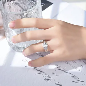 Detalle de un elegante anillo de moissanita de 2 quilates en plata con piedras en la mano.