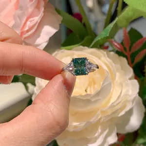 Gros plan d'une bague en moissanite bleu-vert taille radiant avec pierres latérales