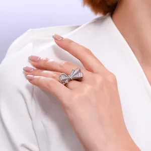 Vista detallada de un elegante anillo de diamantes en forma de lazo usado en una mano.