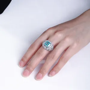 Nahaufnahme eines quadratischen blauen 5-Karat-Diamantrings an einer Frauenhand.