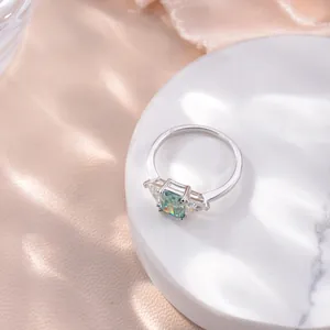 Bague en moissanite bleu-vert taille Radiant, argent plaqué or 18k sur marbre.