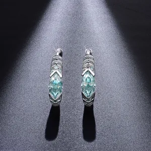 Vista macro de pendientes de moissanita azul verdosa talla marquise con diseño de Horus