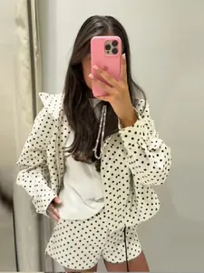 Frau trägt modische weiße Jacke und Shorts mit Punkten in einem Spiegel-Selfie