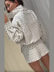 Rückansicht einer Frau in einem modischen gepunkteten Zweiteiler aus Jacke und Shorts