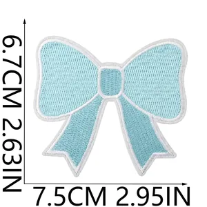 Detail view of a light blue embroidered bow patch with clear size markings in cm and inches