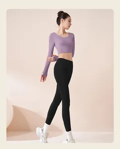 Crop top a maniche lunghe viola e leggings neri aderenti per lo yoga ed il fitness