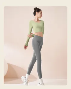 Vista dettagliata del top da yoga verde a maniche lunghe e leggings grigi sulla modella
