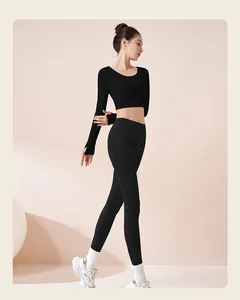 Vista laterale di una modella che indossa un crop top nero a maniche lunghe e leggings da yoga