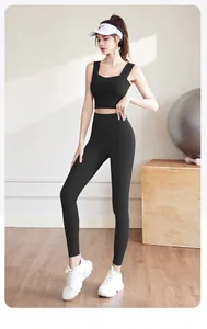 Full body view of a woman wearing a black high-waisted yoga set in a modern fitness gym